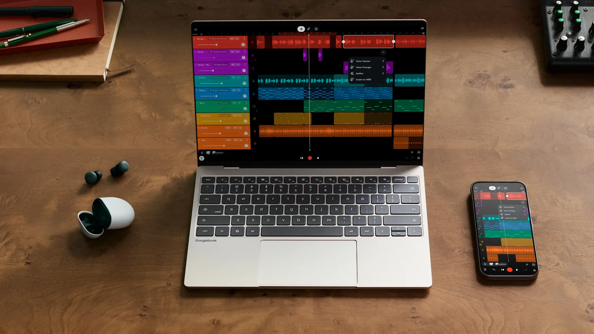 Un Googlebook ouvert sur un bureau en bois, à côté d'un téléphone Android qui affiche la même application de musique